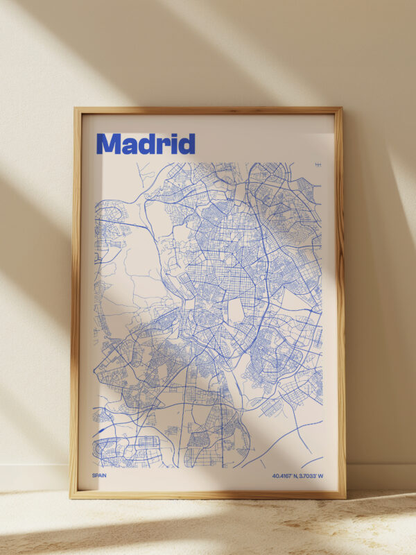 The Madrid City Map Poster features a detailed blue map of Madrid against a white background, framed in natural wood. This art piece is a stylish representation of the city's layout.