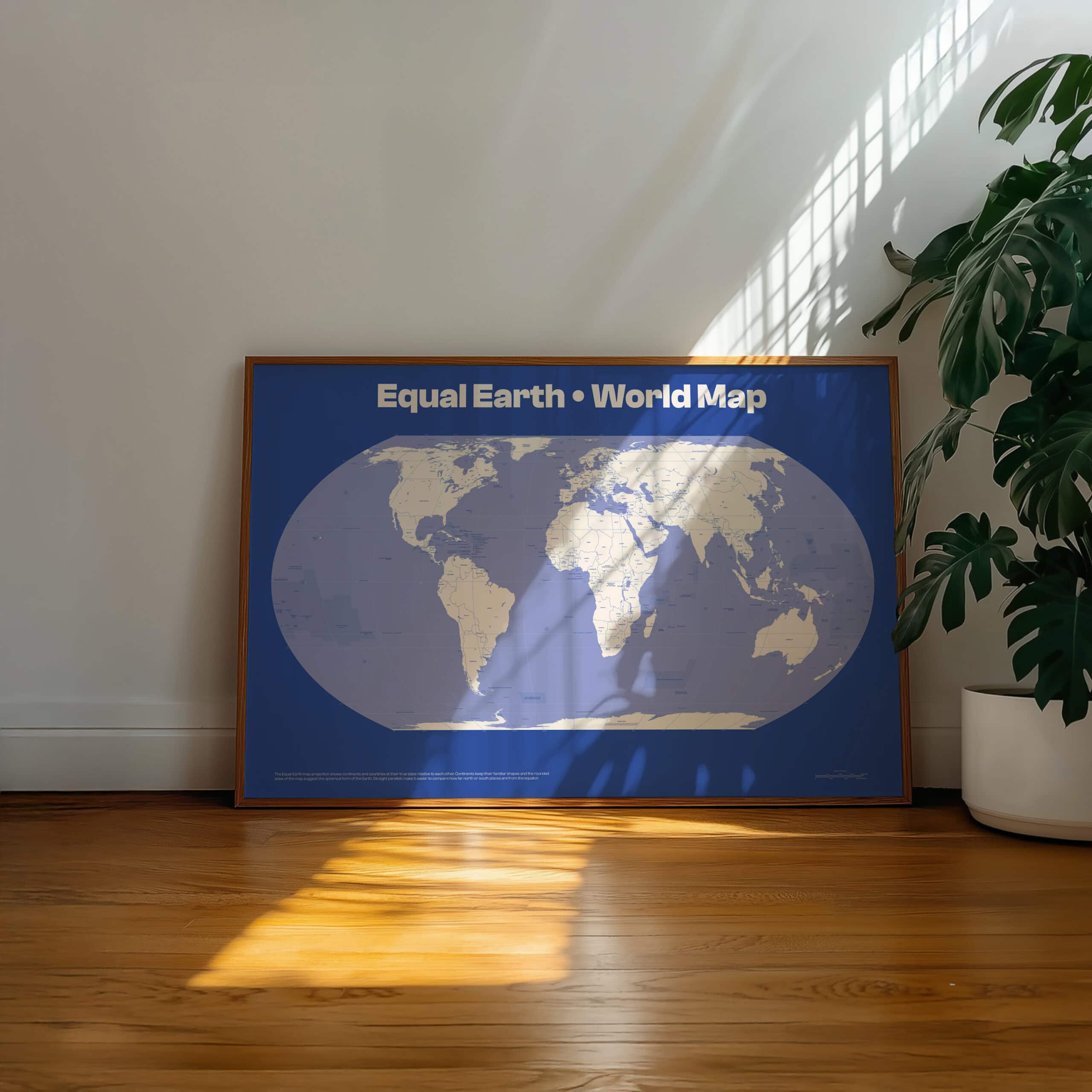 Framed Equal Earth world map print on living room floor with plant