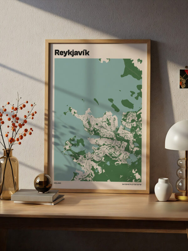 Reykjavik City Map Print in a light wooden frame, featuring a green and white map illustration of Reykjavik. The print sits on a wooden desk, surrounded by decorative items, showcasing the Reykjavik landscape in a modern design.