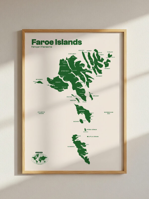 featured-image-3 A framed map of the Faroe Islands displayed on a wall, featuring green landmass outlines on a light background. The title 'Faroe Islands' is printed at the top, with marked locations labeled on the map.