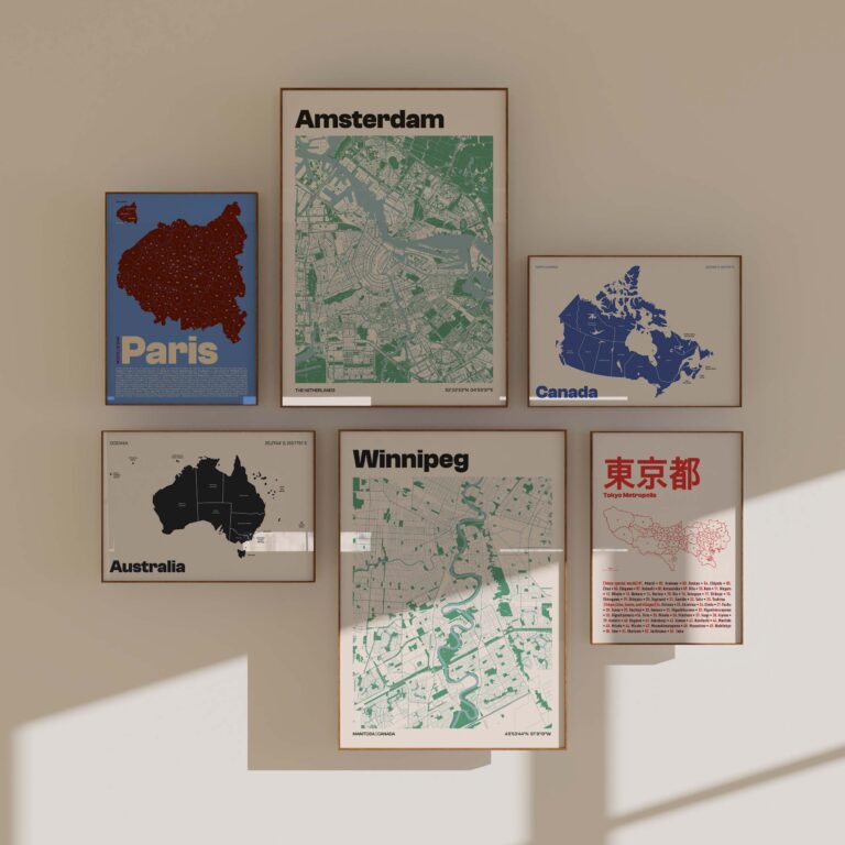 A collection of framed city maps on a light wall, featuring Amsterdam, Canada, Winnipeg, Paris, Tokyo, and Australia, showcasing various colors and styles of geographic designs.