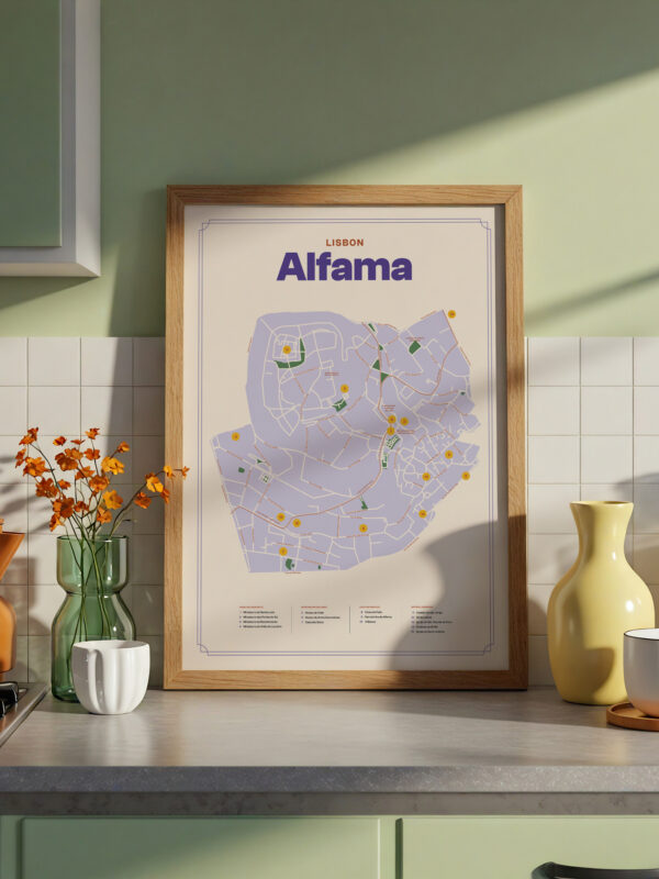 A framed map of Alfama, Lisbon, displayed on a countertop. The map features various marked locations in colors, alongside nearby kitchen items such as a brown kettle, a white cup, a yellow vase, and a glass bottle. Natural light casts shadows on the surface.