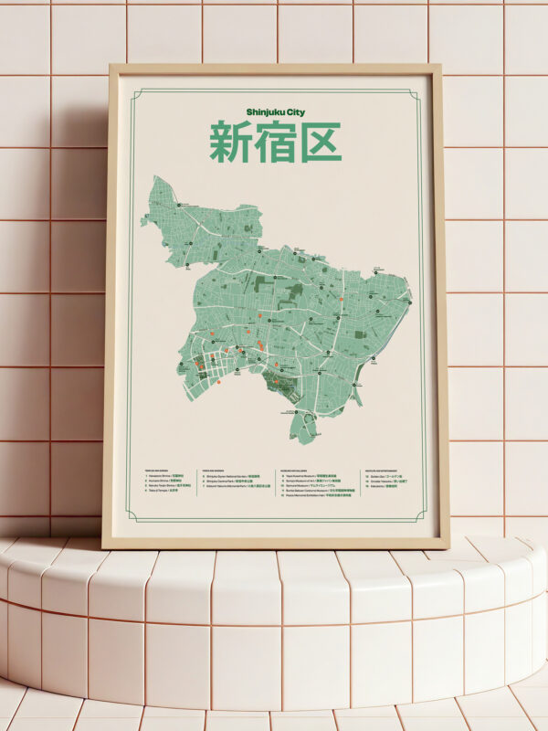 A framed map of Shinjuku City, Japan, displayed on a white tiled pedestal. The map features a green color scheme with intricate details of the area's layout and streets, and includes both English and Japanese text.